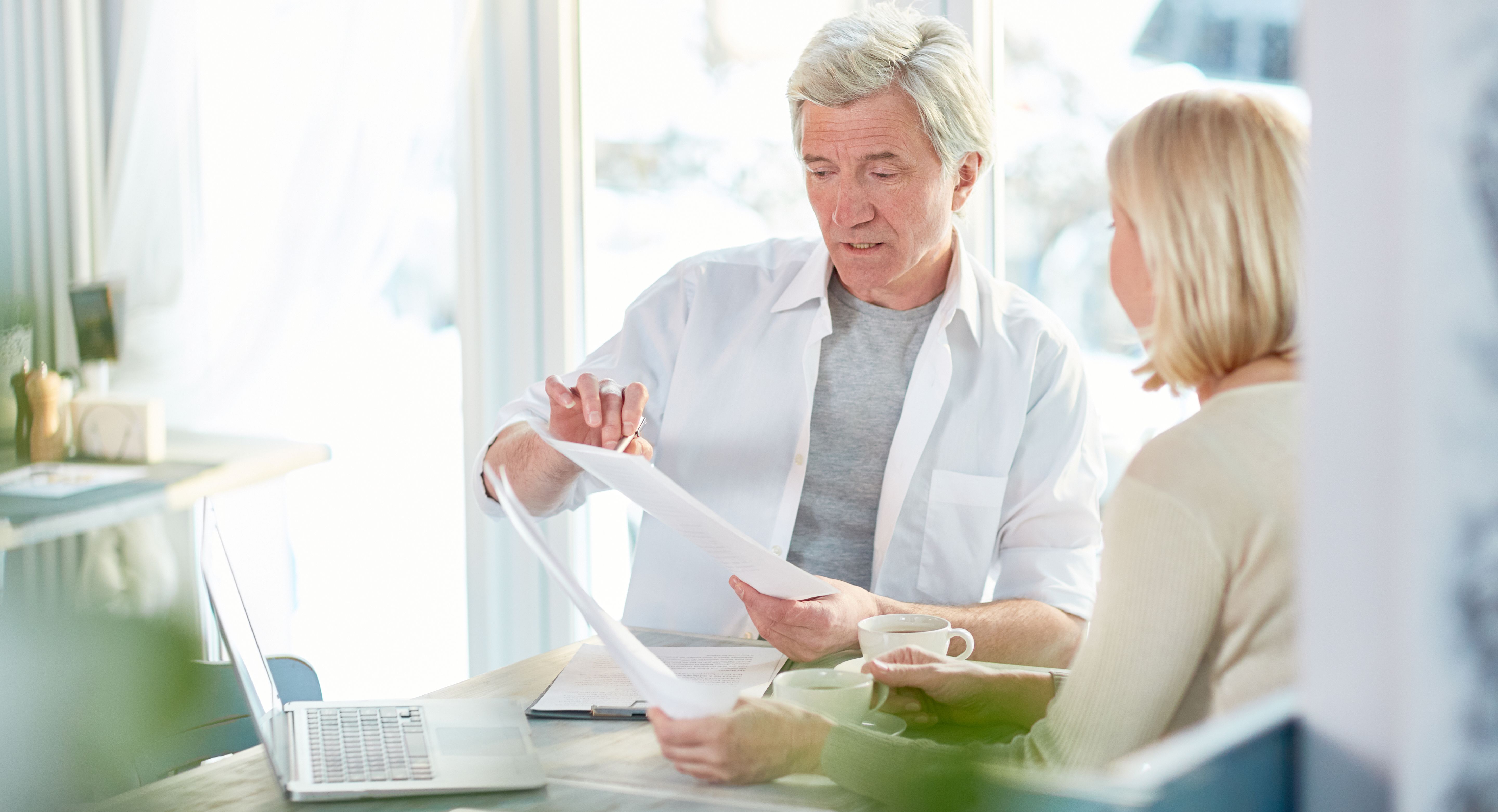 An older man and woman reviewing documents at a table.